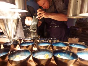 Alliance-Koch reibt Parmesan über kleine Schälchen mit Pasta