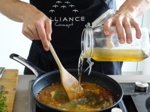 Der Alliance-Koch rührt Gemüsebrühe in eine Pfanne auf dem Herd ein